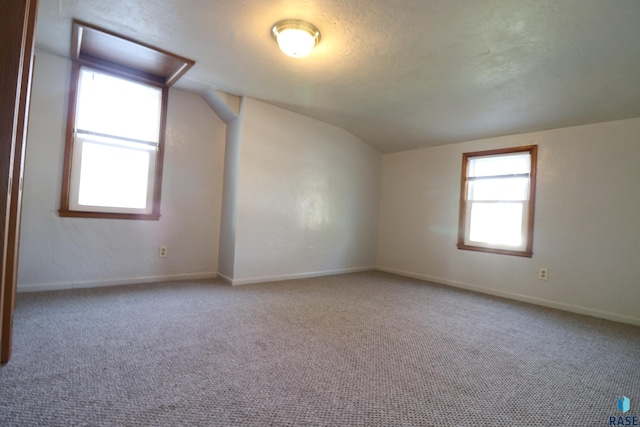 additional living space with vaulted ceiling, carpet floors, and baseboards