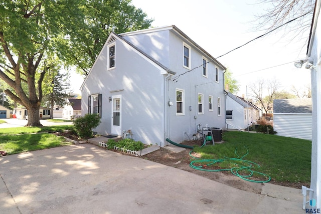 view of front of home with a front lawn, stucco siding, and central air condition unit