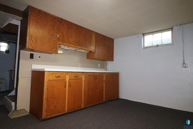 kitchen with brown cabinets, light countertops, and dark colored carpet