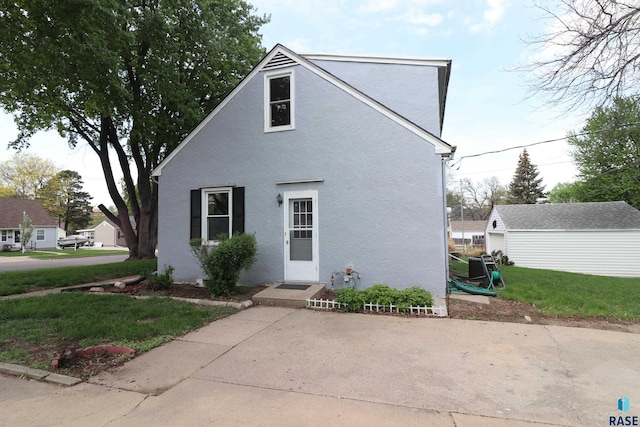 view of front of house with a front yard, stucco siding, and an outbuilding