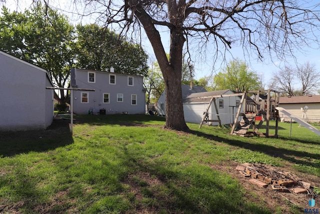 view of grassy yard featuring a playground, an outbuilding, and a storage unit