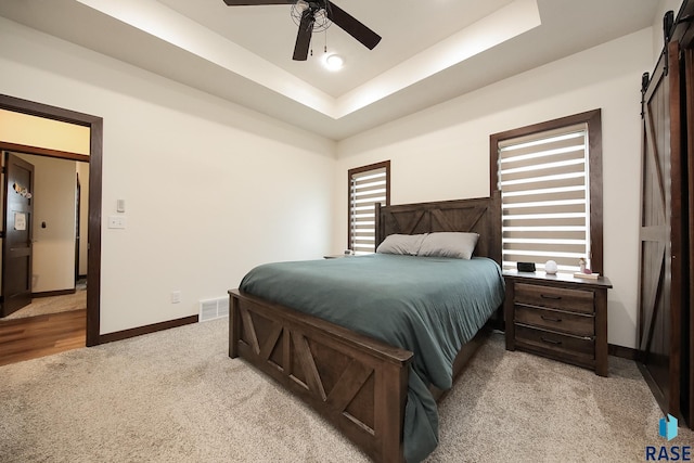 812 Trojan Ave, Hartford, SD 57033 - bedroom featuring a barn door, light carpet, baseboards, and a raised ceiling