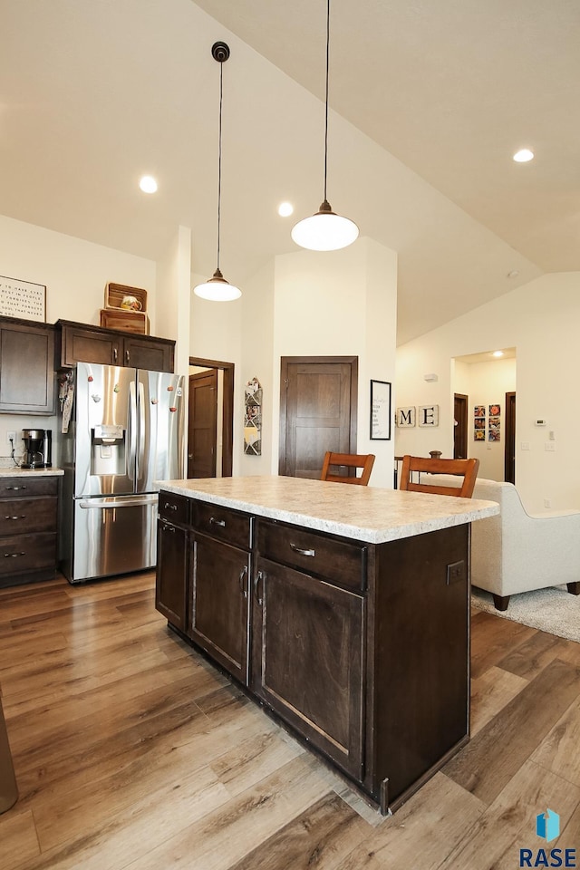 812 Trojan Ave, Hartford, SD 57033 - kitchen with stainless steel refrigerator with ice dispenser, wood finished floors, vaulted ceiling, dark brown cabinets, and a center island