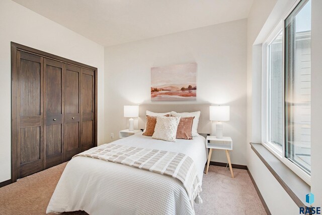 bedroom featuring light colored carpet, baseboards, and a closet