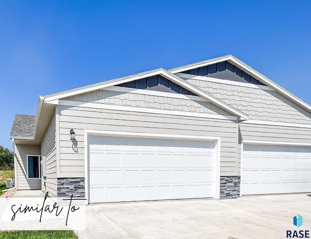 view of front facade with stone siding, a garage, driveway, and board and batten siding