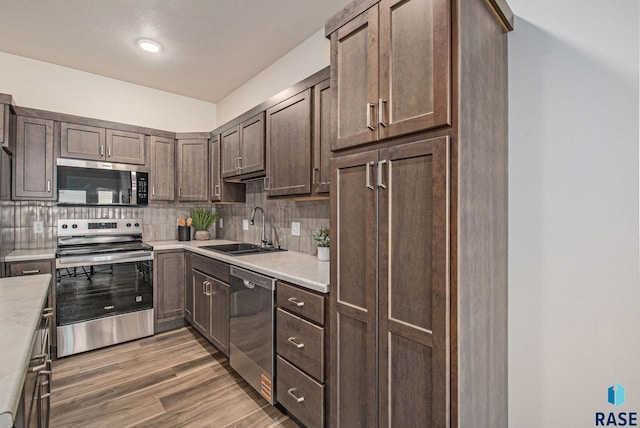 kitchen with appliances with stainless steel finishes, a sink, light countertops, and decorative backsplash