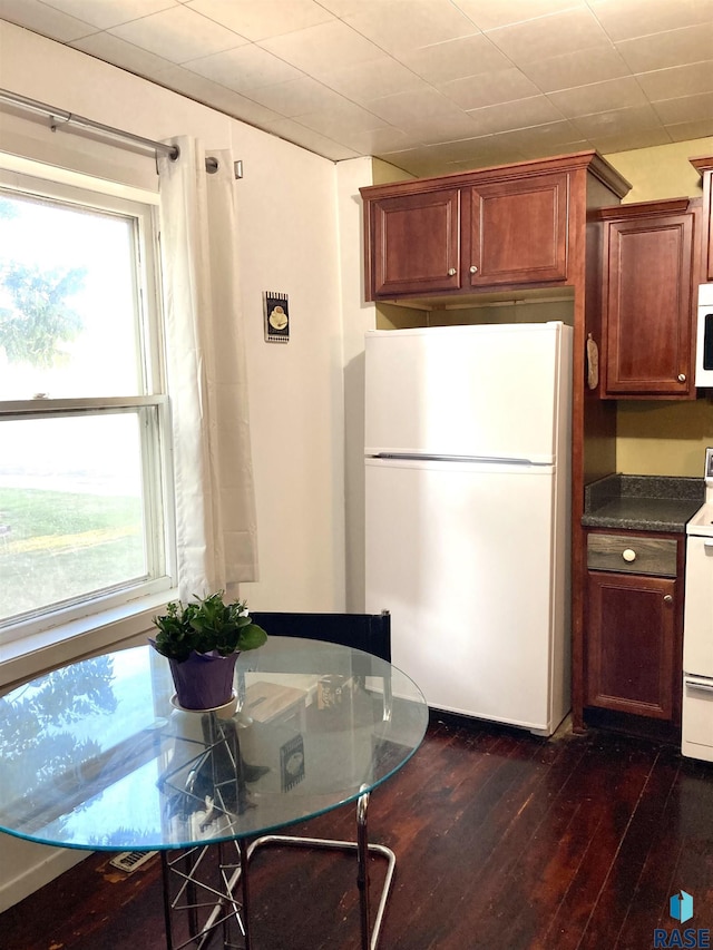 305 S 5th St, Menno, SD 57045 - kitchen with white appliances, dark countertops, dark wood-style floors, and plenty of natural light