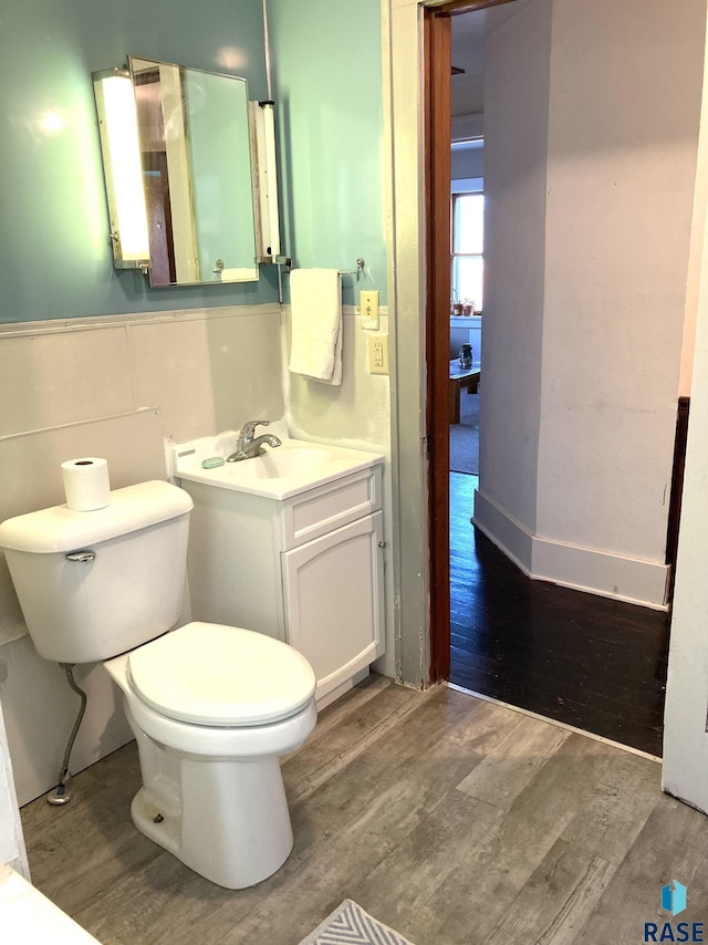 305 S 5th St, Menno, SD 57045 - bathroom featuring wood finished floors, toilet, a wainscoted wall, and vanity