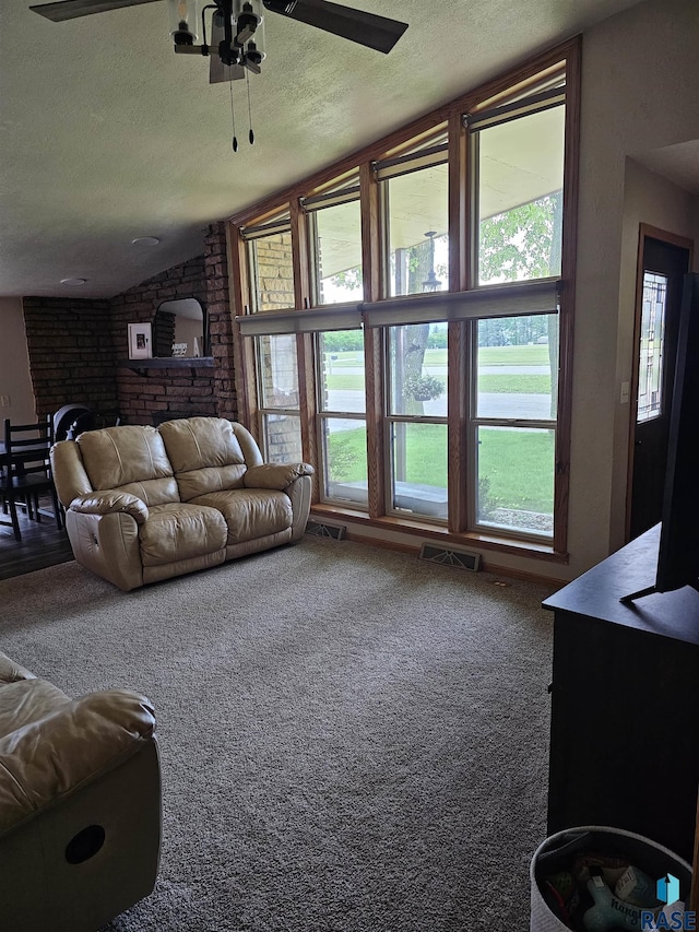 1005 8th Ave, Pipestone, MN 56164 - living room featuring a textured ceiling, a ceiling fan, lofted ceiling, carpet floors, and brick wall