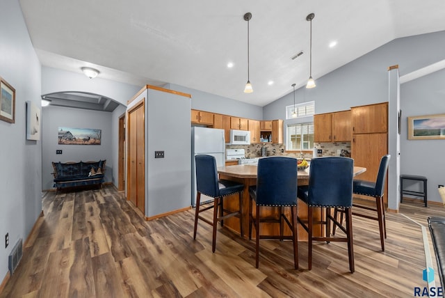 7200 S Hoffman Pl, Sioux Falls, SD 57108 - dining space featuring arched walkways, dark wood-type flooring, baseboards, and high vaulted ceiling