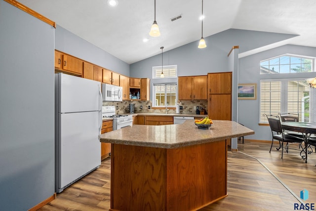 7200 S Hoffman Pl, Sioux Falls, SD 57108 - kitchen with white appliances, vaulted ceiling, backsplash, wood finished floors, and brown cabinets