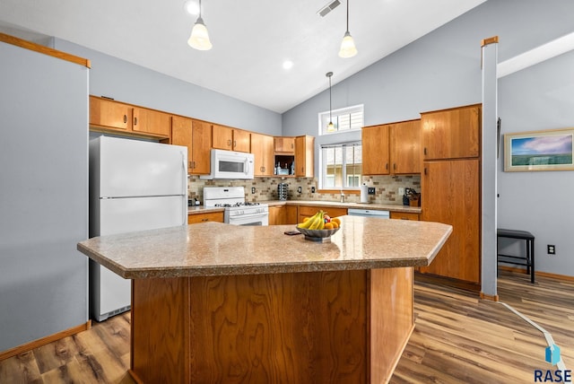 7200 S Hoffman Pl, Sioux Falls, SD 57108 - kitchen with white appliances, wood finished floors, tasteful backsplash, high vaulted ceiling, and brown cabinets