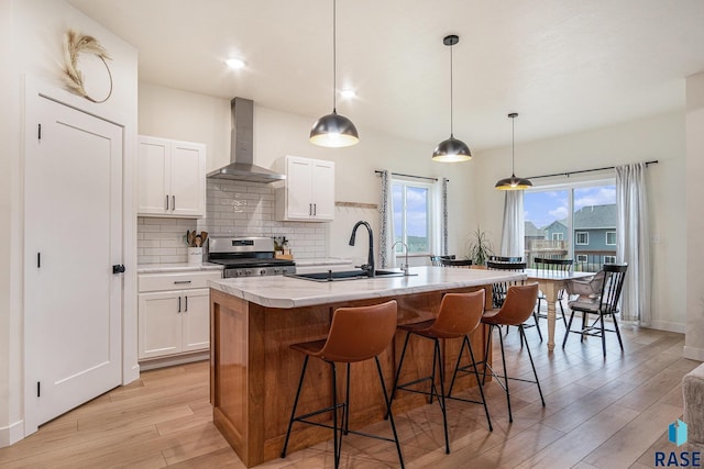 110 Skyline Dr, Valley Springs, SD 57068 - kitchen featuring wall chimney exhaust hood, stainless steel stove, a sink, and light wood-style floors