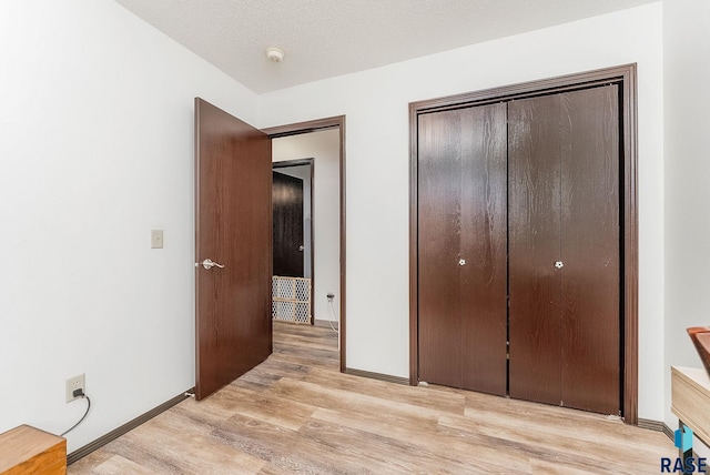 unfurnished bedroom featuring a closet, light wood-style floors, and baseboards