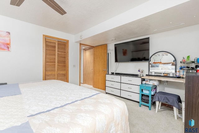 carpeted bedroom with a closet, ceiling fan, and a textured ceiling