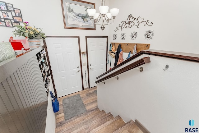foyer featuring light wood-type flooring, a chandelier, and stairway