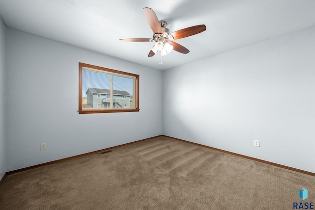 carpeted empty room featuring ceiling fan and baseboards