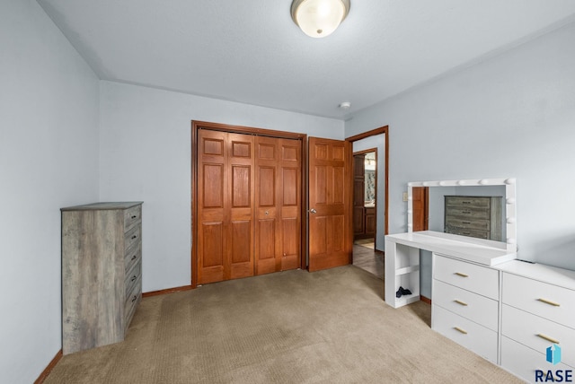 unfurnished bedroom featuring light colored carpet, a closet, and baseboards