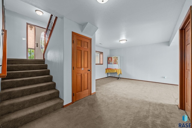 basement featuring carpet flooring, stairs, and baseboards
