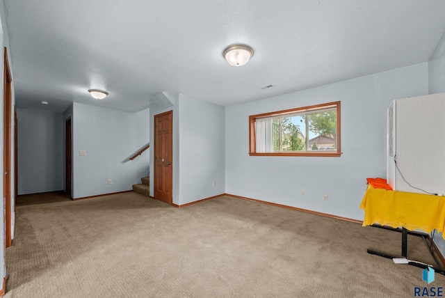 unfurnished room with light colored carpet, stairway, and baseboards