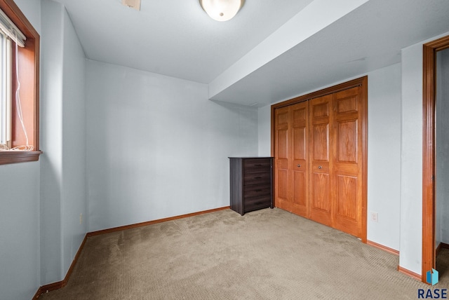unfurnished bedroom featuring light carpet, baseboards, and a closet