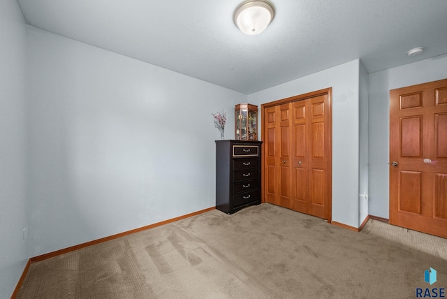 bedroom featuring baseboards, a closet, and light colored carpet