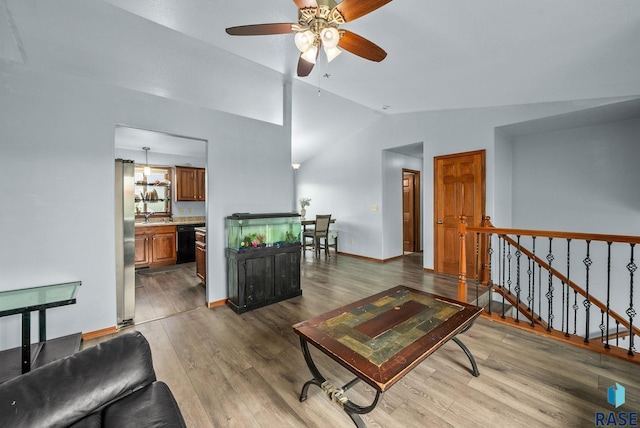 living area with vaulted ceiling, wood finished floors, a ceiling fan, and baseboards