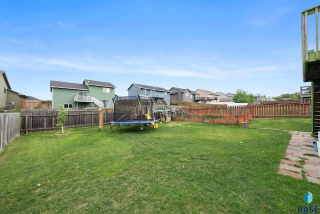 view of yard featuring a trampoline and a residential view