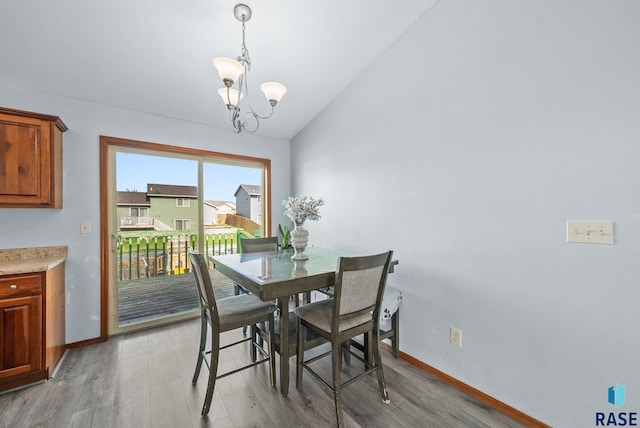 dining space with light wood-style floors, a chandelier, baseboards, and lofted ceiling