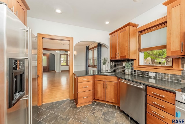 kitchen featuring appliances with stainless steel finishes, arched walkways, a sink, healthy amount of natural light, and recessed lighting