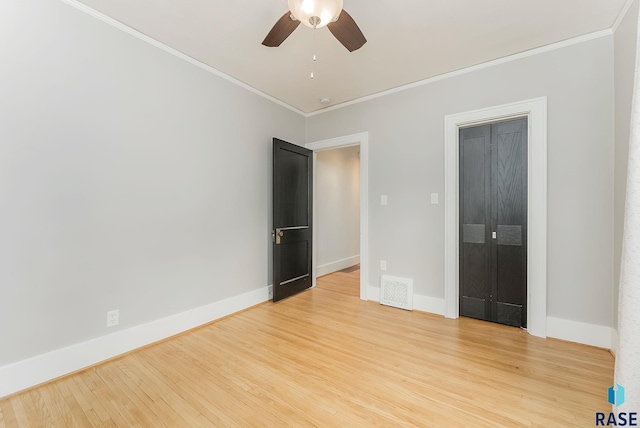 unfurnished bedroom with light wood-type flooring, ornamental molding, baseboards, and a ceiling fan