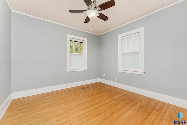 empty room featuring crown molding, wood finished floors, a ceiling fan, and baseboards