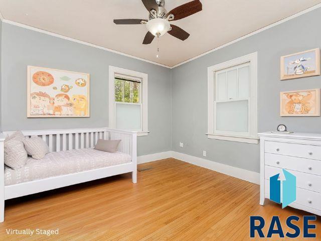 sitting room with crown molding, light wood-style flooring, a ceiling fan, and baseboards