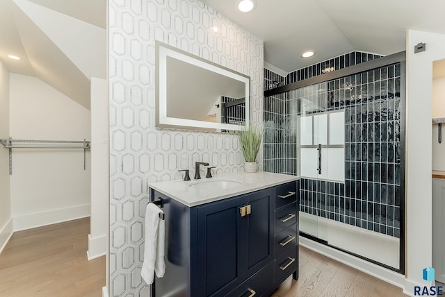 bathroom featuring lofted ceiling, wood finished floors, a shower stall, vanity, and recessed lighting