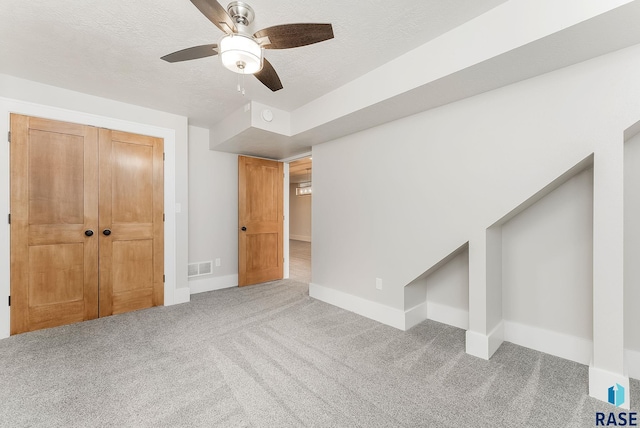 interior space with carpet floors, baseboards, a closet, a textured ceiling, and a ceiling fan