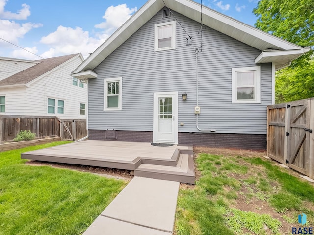 rear view of house with a wooden deck and a gate