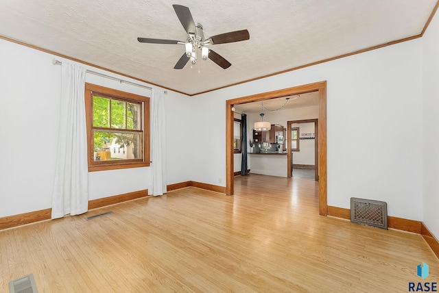 unfurnished room featuring ornamental molding, light wood-style flooring, a ceiling fan, baseboards, and a textured ceiling