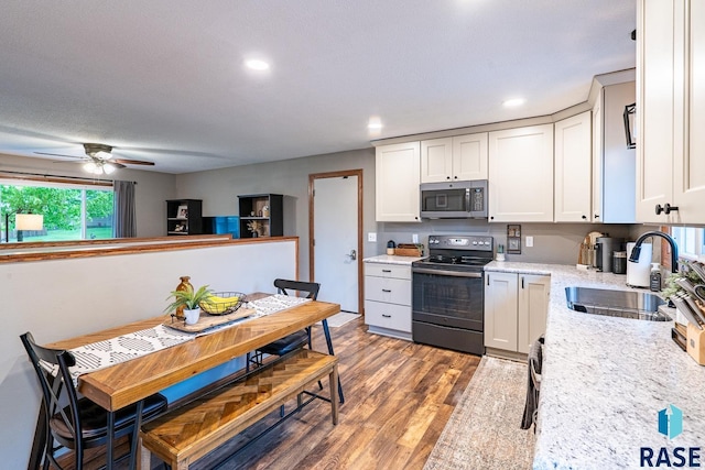 kitchen featuring black range with electric stovetop, stainless steel microwave, a sink, wood finished floors, and a ceiling fan