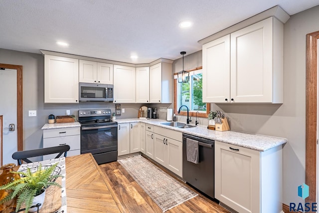 kitchen with stainless steel appliances, a sink, recessed lighting, wood finished floors, and white cabinetry