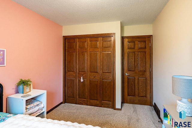carpeted bedroom with a closet and a textured ceiling