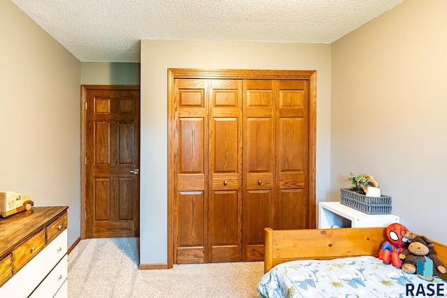 carpeted bedroom featuring a textured ceiling, a closet, and baseboards