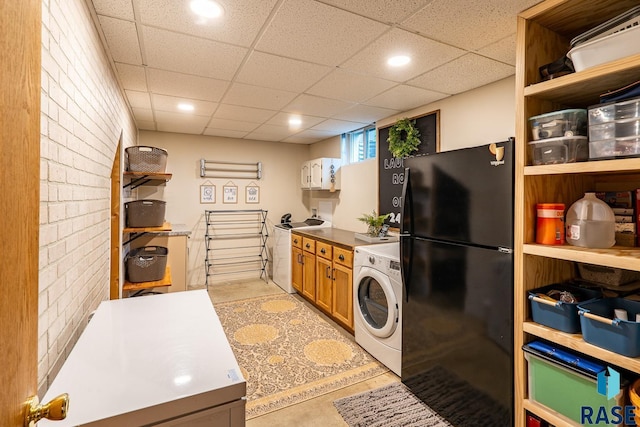 kitchen featuring washer / clothes dryer, freestanding refrigerator, a drop ceiling, recessed lighting, and brown cabinets