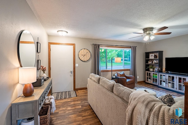 living room featuring dark wood-type flooring, a textured ceiling, ceiling fan, and baseboards