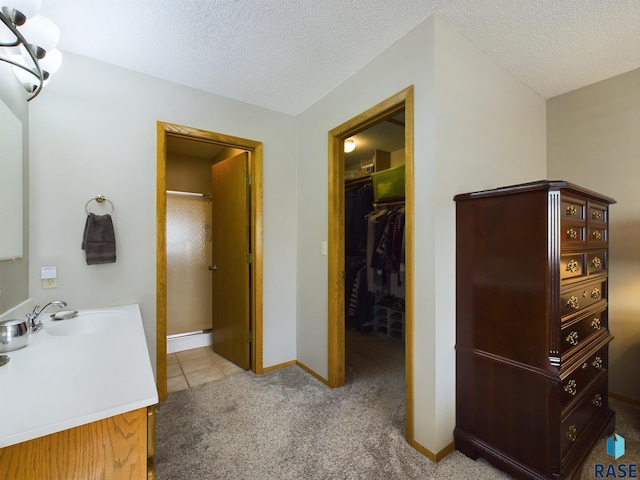 2904 E 52nd St, Sioux Falls, SD 57103 - full bathroom featuring a shower stall, a textured ceiling, a walk in closet, baseboards, and tile patterned flooring