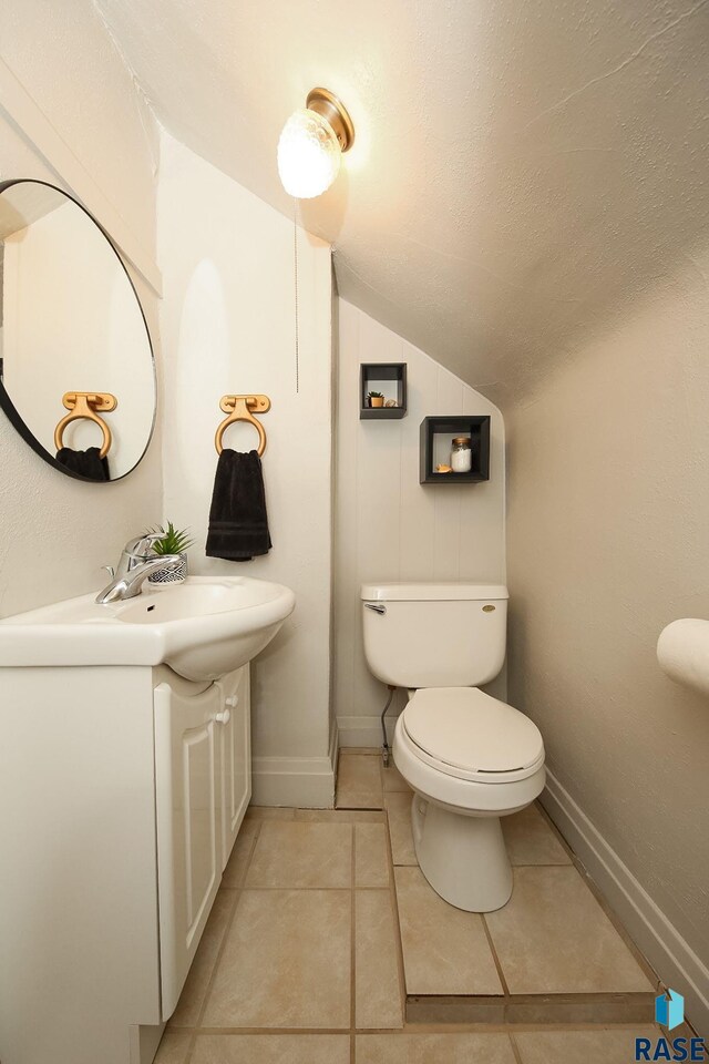 105 N 7th St, Beresford, SD 57004 - bathroom featuring lofted ceiling, vanity, toilet, baseboards, and tile patterned floors