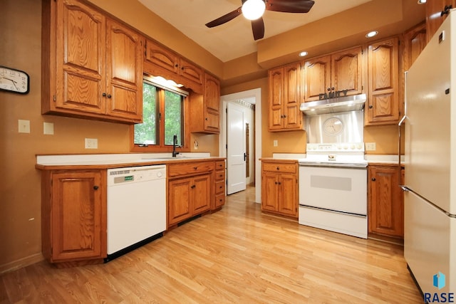 105 N 7th St, Beresford, SD 57004 - kitchen featuring white appliances, under cabinet range hood, a sink, light countertops, and brown cabinetry