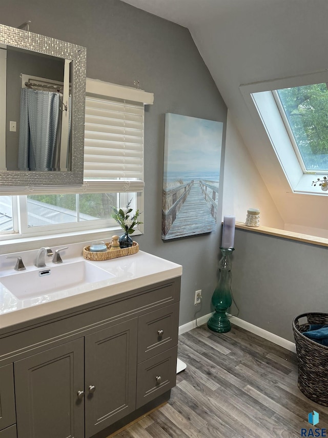 401 W 16th St, Tyndall, SD 57066 - bathroom with a skylight, vaulted ceiling, vanity, wood finished floors, and healthy amount of natural light