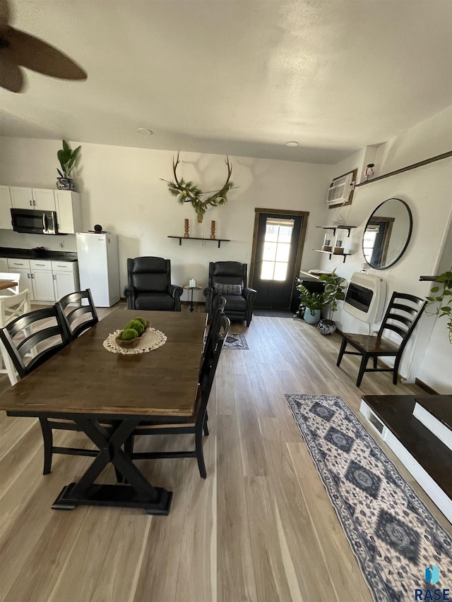 401 W 16th St, Tyndall, SD 57066 - dining area featuring light wood-style floors, heating unit, a ceiling fan, and a wall unit AC