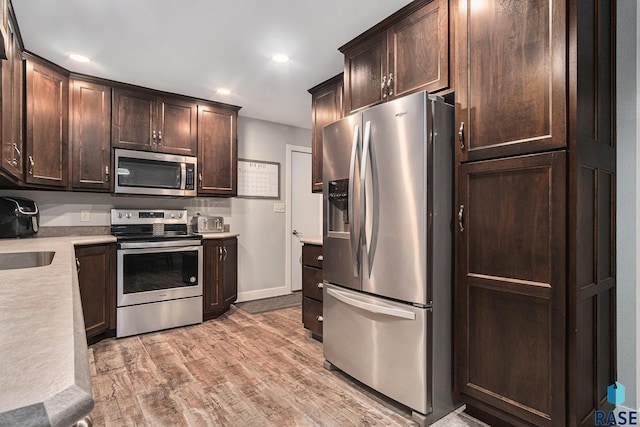 1034 N Elmwood Ave, Luverne, MN 56156 - kitchen featuring stainless steel appliances, dark brown cabinetry, light countertops, light wood finished floors, and recessed lighting