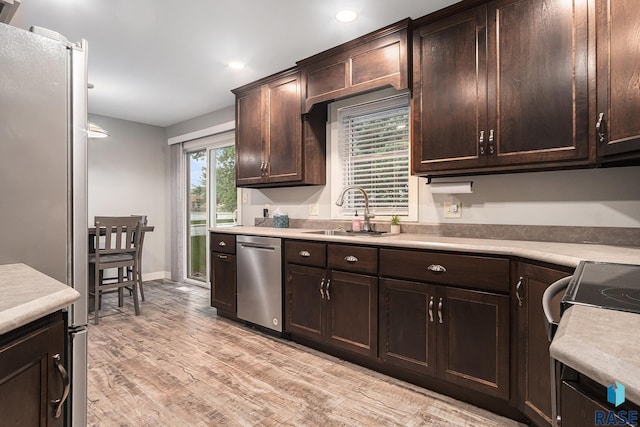 1034 N Elmwood Ave, Luverne, MN 56156 - kitchen with stainless steel appliances, a sink, light countertops, dark brown cabinetry, and light wood finished floors